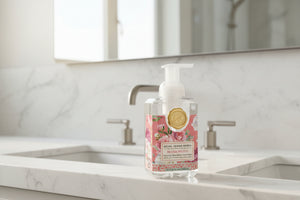 Foaming hand soap bottle with floral design and gold emblem on a white background