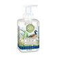 A clear pump bottle of Michel Design Works By the Lake foaming hand soap with a decorative label featuring a duck, reeds, and a serene lake scene.