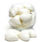 A clear glass bowl filled with small white heart-shaped soaps. Some soaps are also placed outside of the bowl.